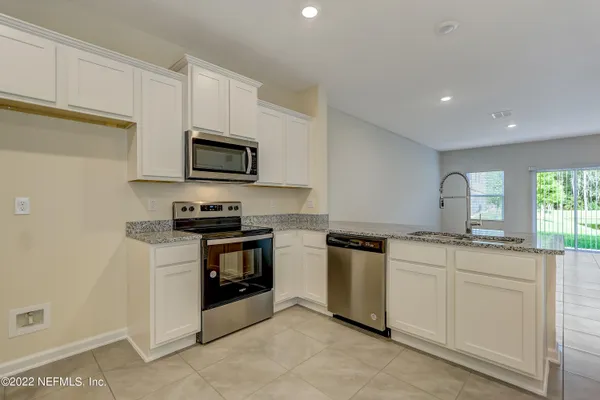 a kitchen with granite countertop white cabinets and stainless steel appliances