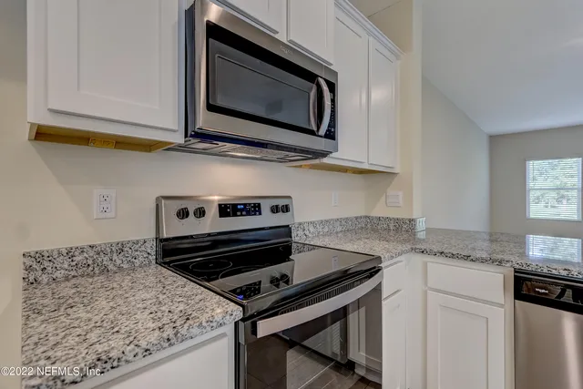 a kitchen with granite countertop a stove microwave and sink