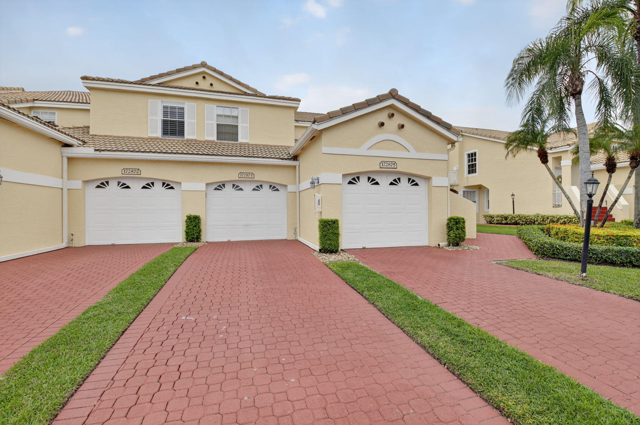 17287 Boca Club Boulevard, Unit 1 Boca Raton, FL 33487 - Photo 2 of 28 a front view of a house with a yard and garage