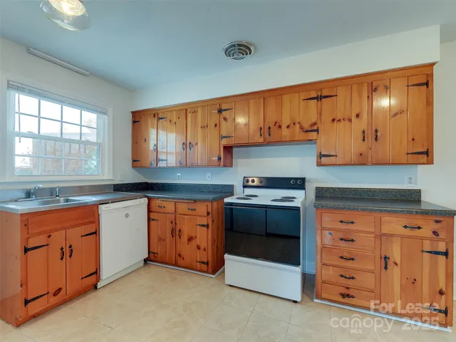 a kitchen with granite countertop a sink cabinets stainless steel appliances and a window