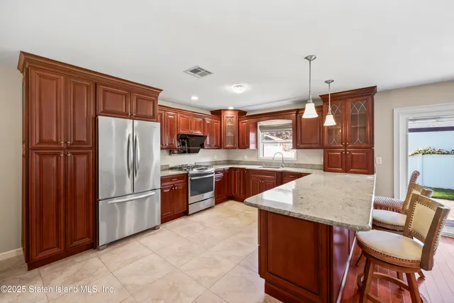 a kitchen with stainless steel appliances granite countertop a refrigerator a sink dishwasher and a stove with wooden cabinets