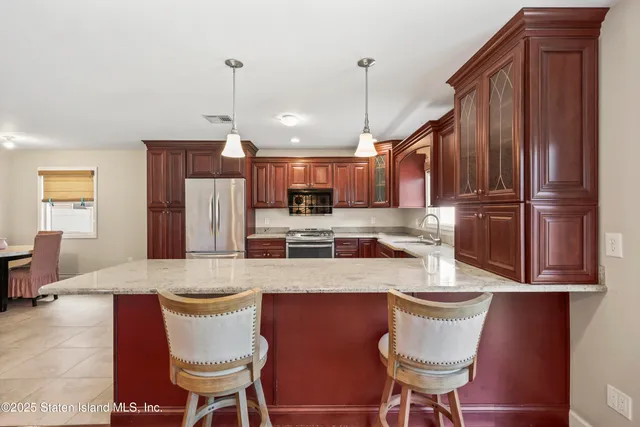 a kitchen with stainless steel appliances granite countertop a sink a stove a refrigerator and wooden cabinets