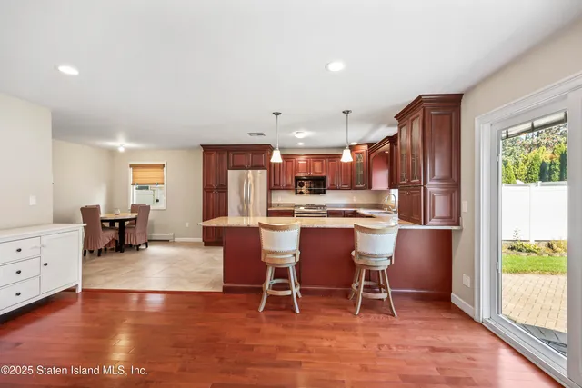 a living room with stainless steel appliances kitchen island granite countertop furniture and a wooden floor