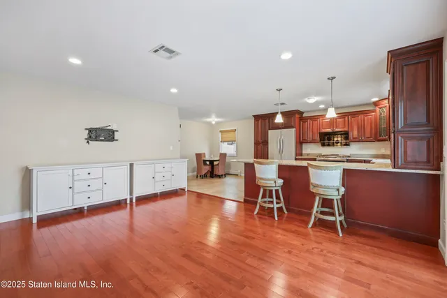 a living room with stainless steel appliances furniture cabinets and wooden floor