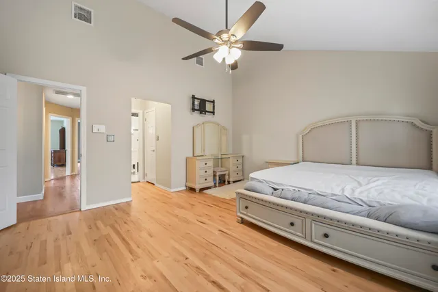 a view of a hallway with wooden floor and a bathroom