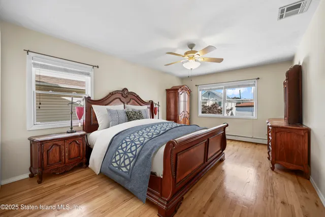 a bedroom with a bed and a dresser with wooden floor