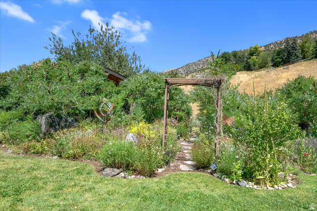 510 Spring Creek Road Providence, UT 84332 - Photo 72 of 97 Garden pathway with stone steps and a wooden archway, surrounded by diverse plantings