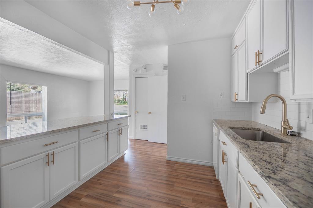 4723 Victor Street, Unit B Dallas, TX 75246 - Photo 10 of 12 Modern kitchen featuring white shaker cabinetry with gold-toned hardware, stone-finish countertops, subway tile backsplash, a stainless steel sink, and wood-finish flooring