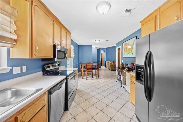 a kitchen with stainless steel appliances granite countertop a refrigerator a sink a stove and white cabinets