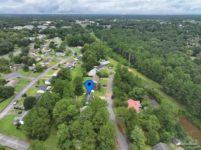 an aerial view of residential houses with outdoor space and trees all around