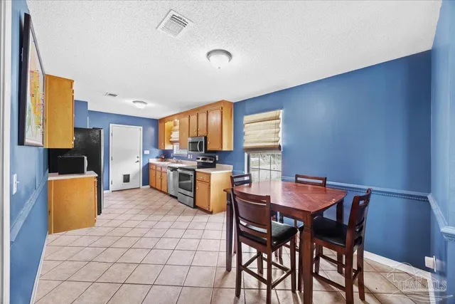 a kitchen with stainless steel appliances a dining table chairs and a refrigerator