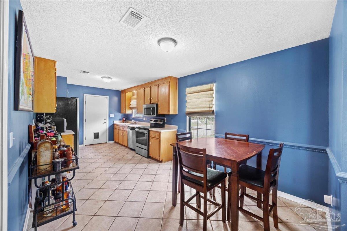 8617 Blue Jay Way Pensacola, FL 32534 - Photo 4 of 28 a kitchen with stainless steel appliances a table and chairs in it