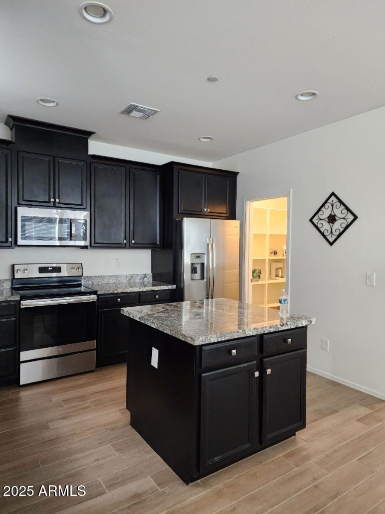 14870 West Encanto Boulevard, Unit 1113 Goodyear, AZ 85395 - Photo 12 of 33 a kitchen with stainless steel appliances granite countertop a stove a sink and a microwave