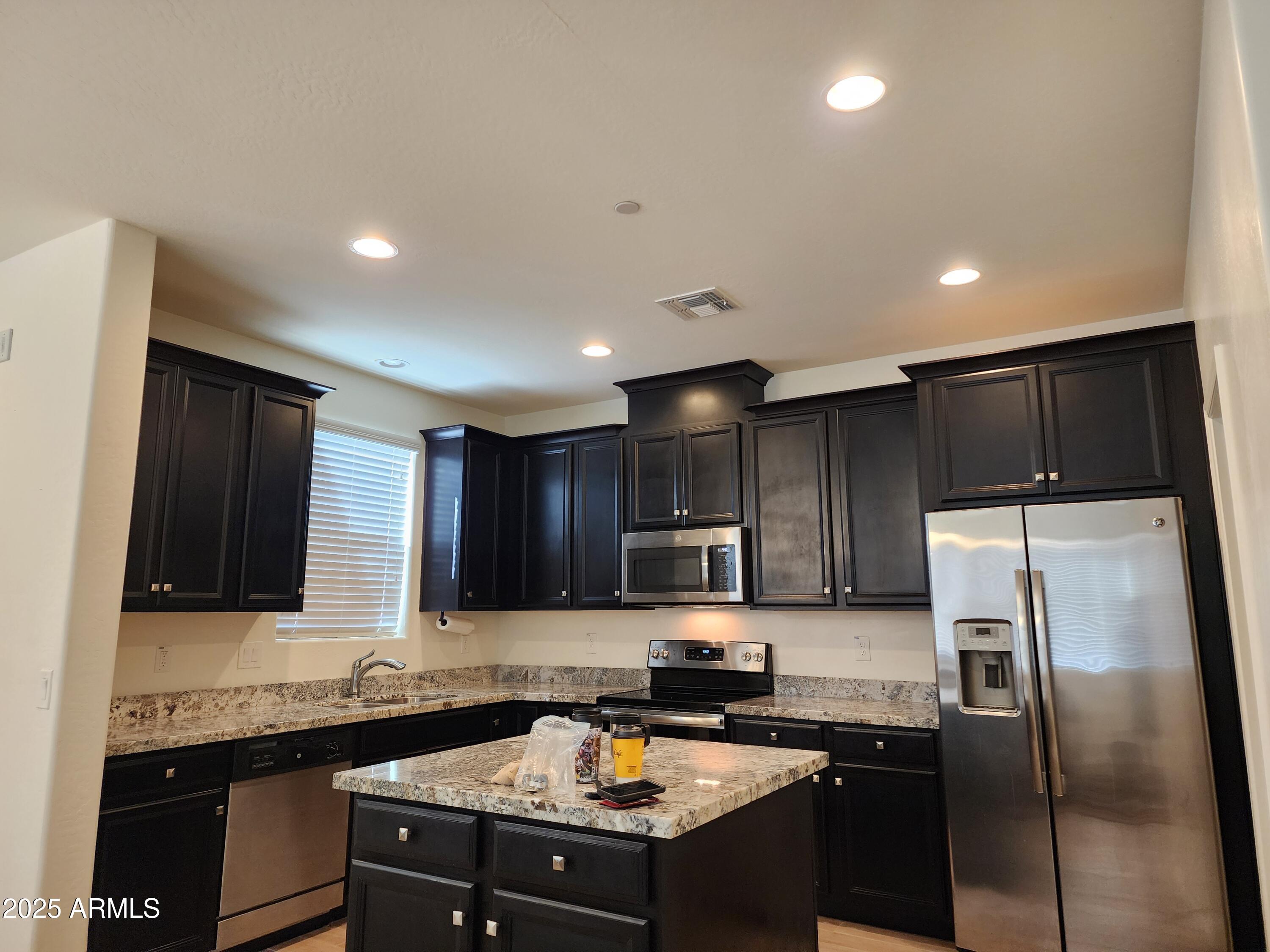 14870 West Encanto Boulevard, Unit 1113 Goodyear, AZ 85395 - Photo 13 of 33 a kitchen with a sink a stove a refrigerator and cabinets
