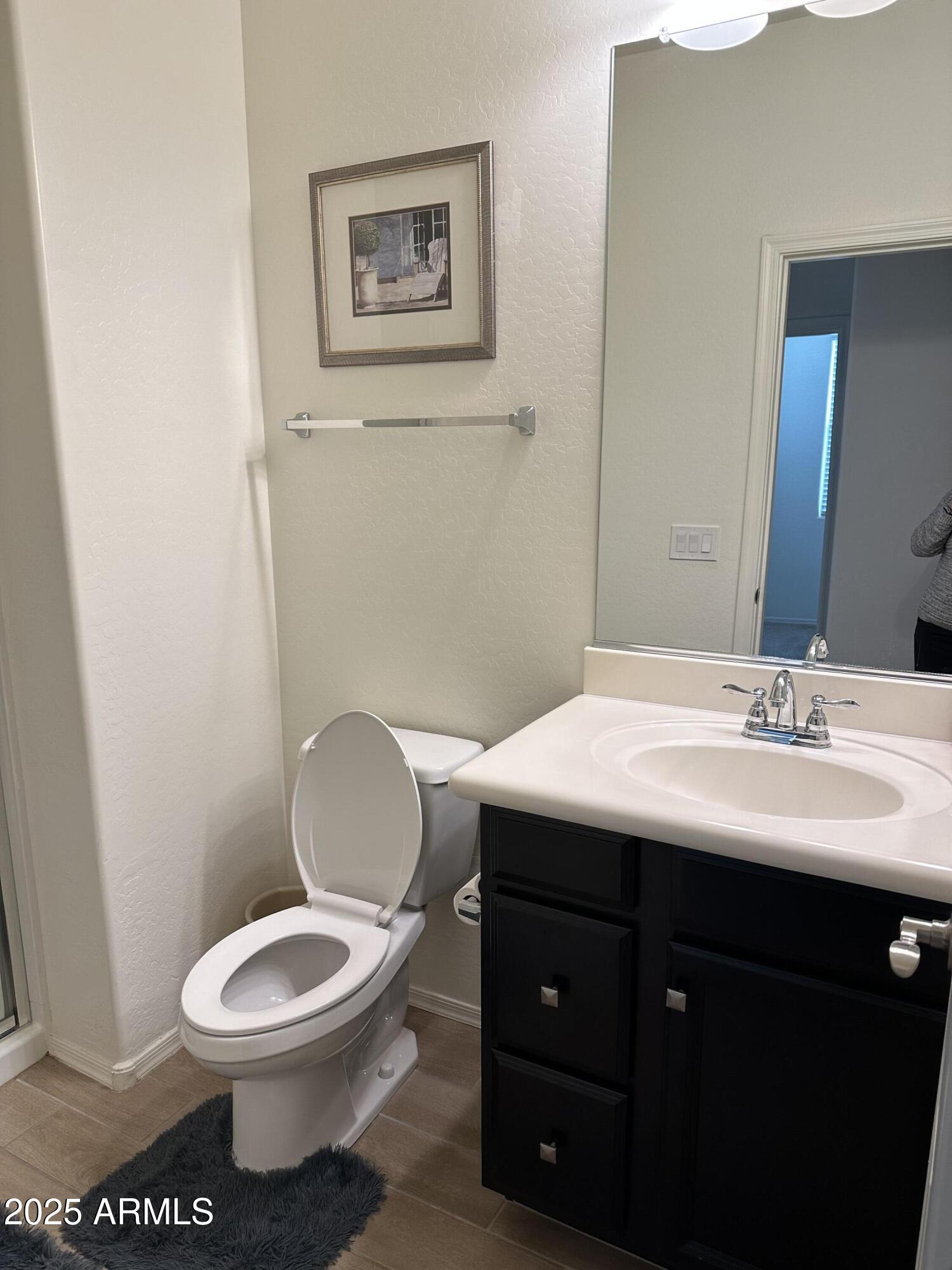 14870 West Encanto Boulevard, Unit 1113 Goodyear, AZ 85395 - Photo 17 of 33 a bathroom with a toilet a sink and mirror