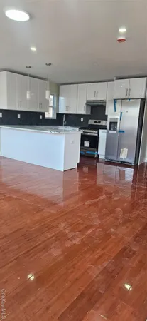 a large kitchen with stainless steel appliances a large counter top a stove a sink and a refrigerator