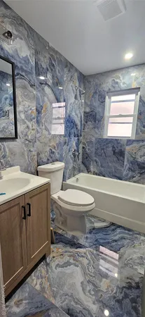 a bathroom with a granite countertop toilet a sink and a bathtub