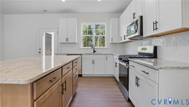 a kitchen with stainless steel appliances granite countertop a stove a sink and a microwave