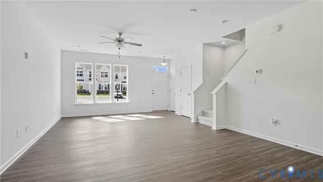 an empty room with wooden floor ceiling fan and windows