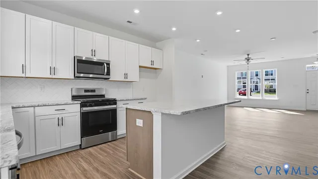 a kitchen with granite countertop a stove top oven a sink dishwasher and a refrigerator with wooden floor