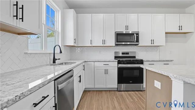 a kitchen with stainless steel appliances granite countertop a sink stove and white cabinets with wooden floor