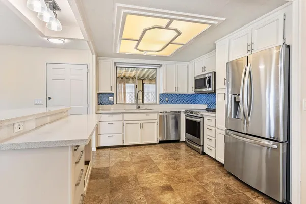 a kitchen with white cabinets and stainless steel appliances