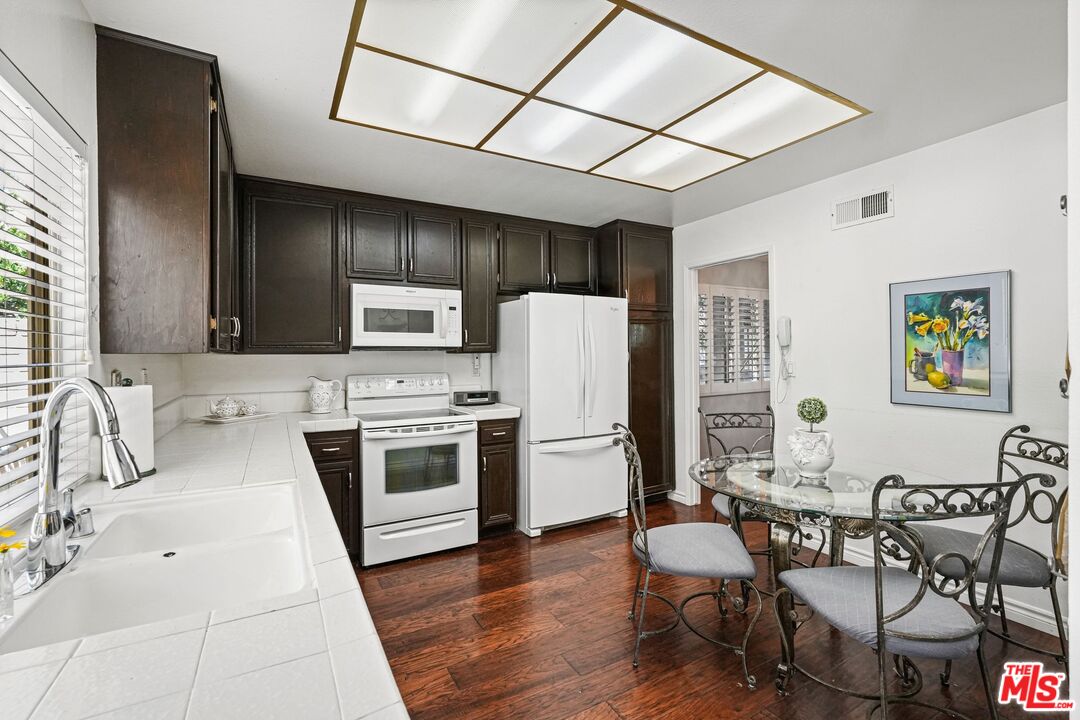 10621 Vanalden Avenue Porter Ranch, CA 91326 - Photo 19 of 38 a kitchen with stainless steel appliances a stove a sink dishwasher a refrigerator with a dining table and chairs