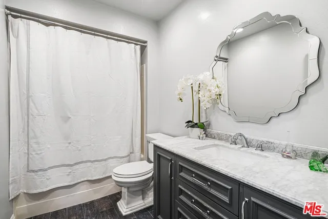a bathroom with a granite countertop sink toilet and shower