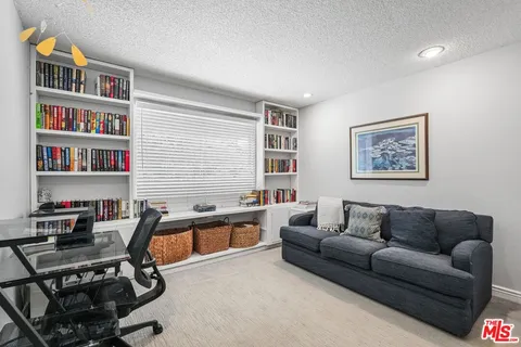 a living room with furniture a bookshelf and a window