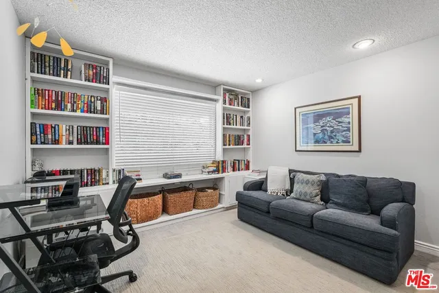 a living room with furniture a bookshelf and a window