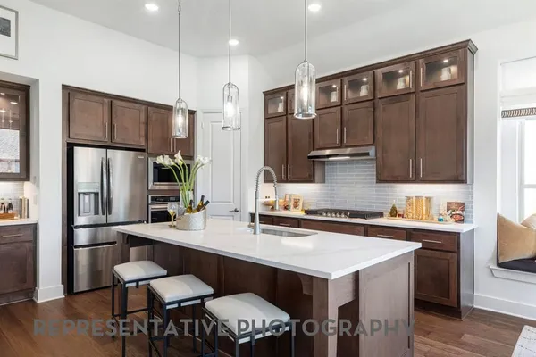 a kitchen with stainless steel appliances a sink a stove a refrigerator and chairs