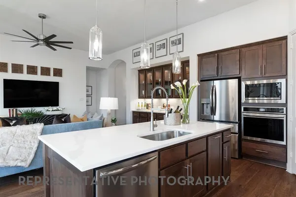 a kitchen with a sink stainless steel appliances a counter top space and living room view