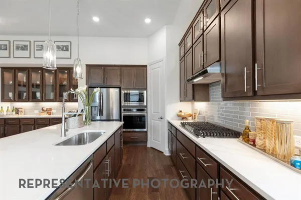 a kitchen with stainless steel appliances granite countertop a sink a stove and a wooden floors