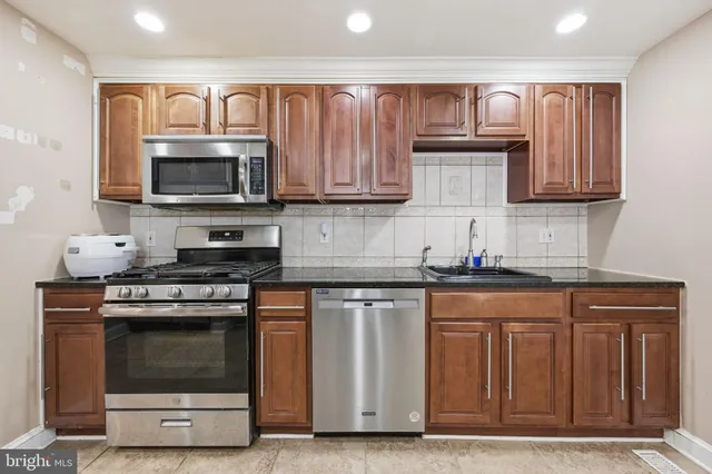 a kitchen with granite countertop a stove top oven microwave and cabinets