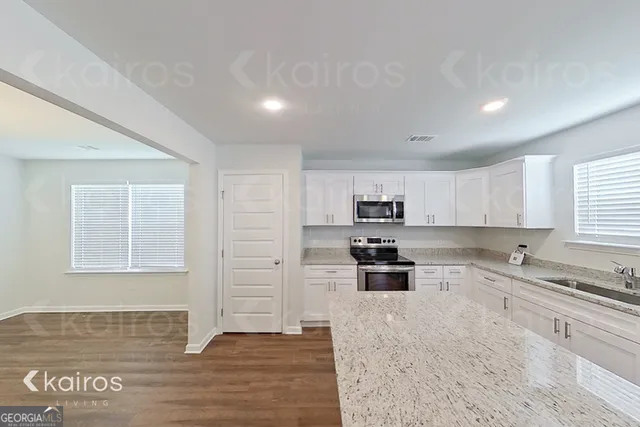 a kitchen with granite countertop a stove a sink and a refrigerator