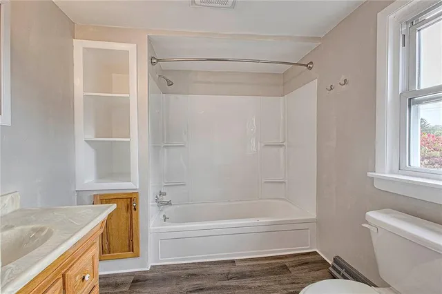 a bathroom with a granite countertop bathtub shower sink vanity and toilet