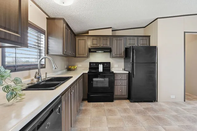 a kitchen with granite countertop a refrigerator stove and sink