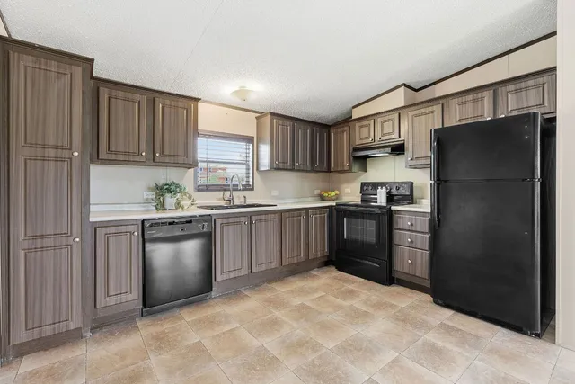 a kitchen with granite countertop a refrigerator stove top oven and sink