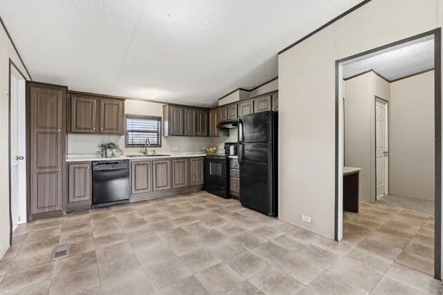 a kitchen with granite countertop a refrigerator and a stove top oven