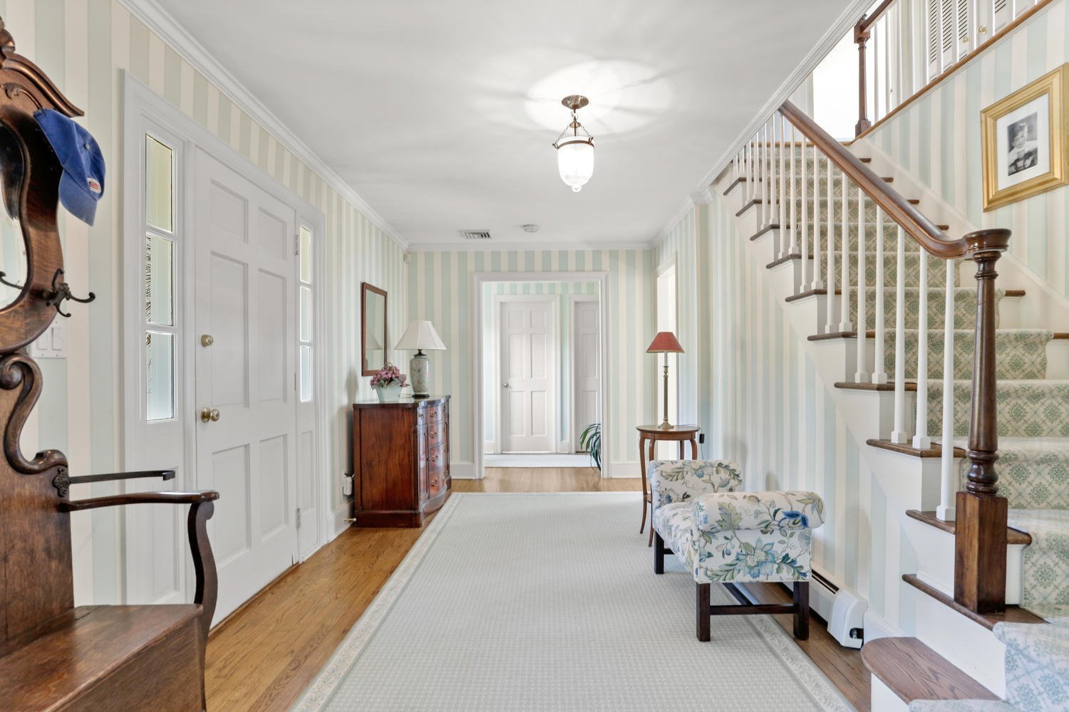 116 Marshall Ridge Road New Canaan, CT 06840 - Photo 16 of 50 a hallway with chandelier and wooden floor