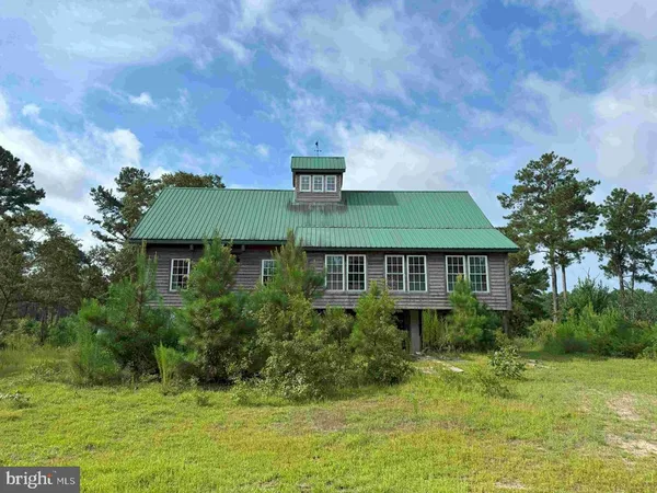 a view of a backyard with large trees and a barn