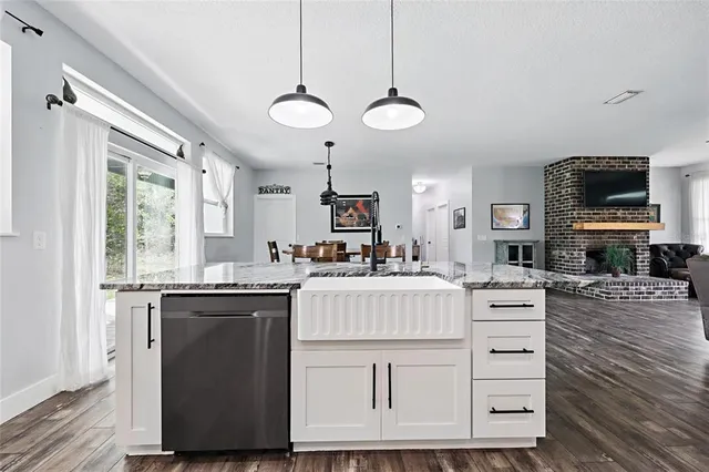 a kitchen with stainless steel appliances granite countertop a sink a stove a refrigerator cabinets and chairs