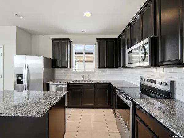 a kitchen with stainless steel appliances granite countertop a sink stove microwave and refrigerator