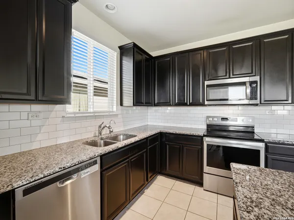 a kitchen with stainless steel appliances granite countertop wooden cabinets and a stove top oven