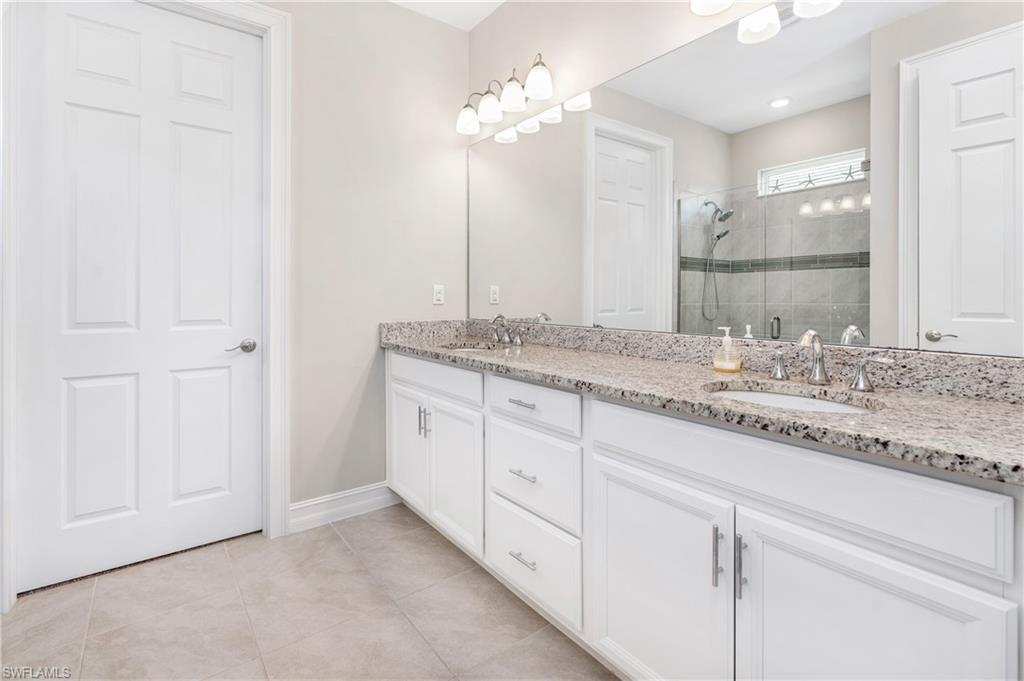 14488 Stillwater Way Naples, FL 34114 - Photo 18 of 37 a bathroom with a granite countertop double vanity sink a mirror and shower