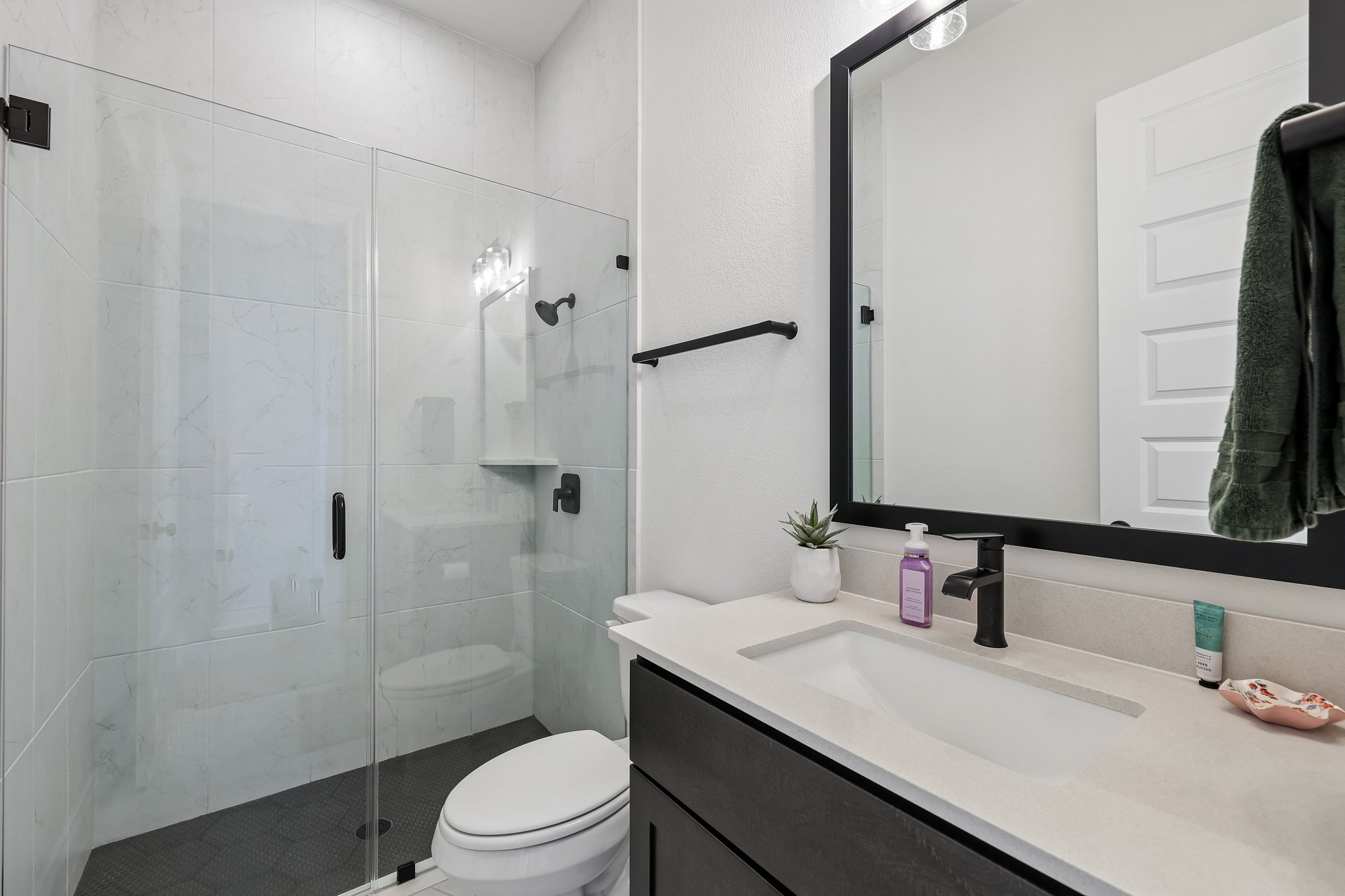 130 Firethorn Loop Bastrop, TX 78602 - Photo 17 of 38 Contemporary bathroom featuring a frameless glass shower enclosure with white tiled walls and a dark tiled floor