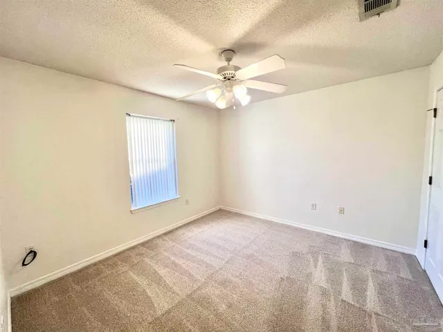 an empty room with windows and fan
