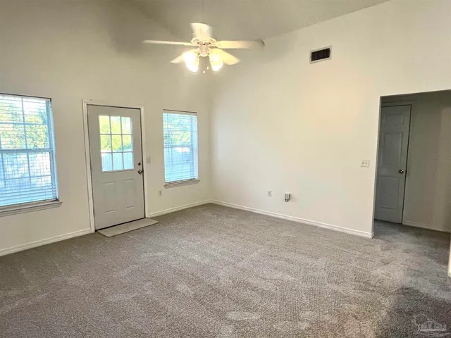 an empty room with windows and fan