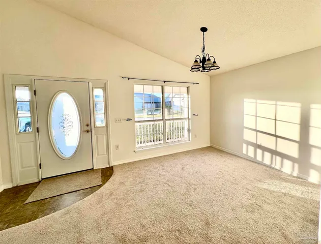 a view of a room with wooden floor chandelier and windows
