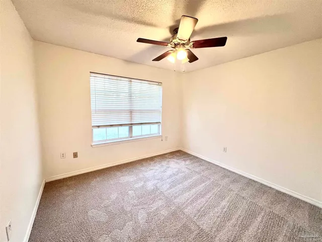 an empty room with window and ceiling fan